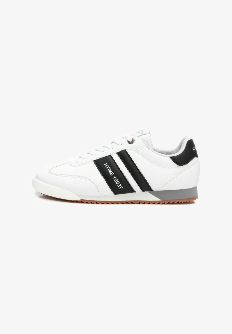 Sneaker bianca con strisce nere, dotata di una suola in gomma testurizzata, punta con lacci e accento grigio sul tallone. Logo del marchio di lato.