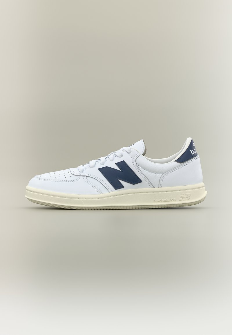 Λευκό χαμηλό παπούτσι New Balance με ναυτικό λογότυπο "N" και ταμπελάκι στη φτέρνα, εκρού σόλα και κλείσιμο με κορδόνια.