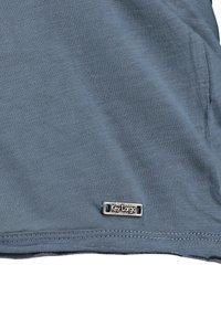 Niebieska bawełniana koszulka o gładkiej fakturze, z metalową etykietą "Key Largo" w kolorze srebrnym umieszczoną blisko dolnego szwu oraz subtelnymi detalami w szwach.