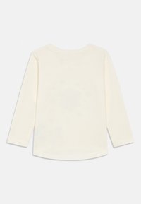 Maglietta a maniche lunghe in cotone color crema. Presenta un collo rotondo e un orlo dritto. Tessuto morbido senza motivi o decorazioni visibili.