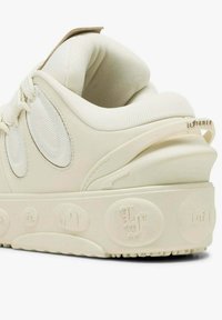 Krémově zbarvený podpatek tenisky s polstrovaným límcem, texturovaným bočním panelem z tkaniny mesh, reliéfní podrážkou s dekorativními iniciály a textilní smyčkou označenou "la france".