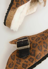 Leopardmuster Hausschuhe bestehen aus braunem Wildleder, haben ein Futter aus Kunstpelz und eine schwarze Schnallenakzent. Kork-Mittelsohle und strukturierten schwarzen Außensohle.