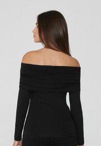Schwarzes, schulterfreies Top mit langen Ärmeln, drapierter Ausschnitt und figurnahes Design, aus glattem Stoff gefertigt, das eine schlanke Silhouette zeigt.