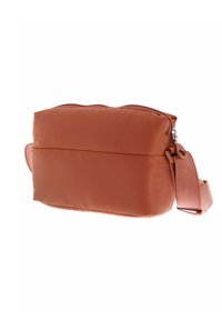 Sac en tissu doux de couleur terre cuite avec fermeture éclair, forme rectangulaire et large sangle. Surface texturée et design minimaliste.