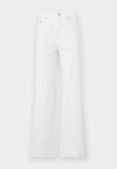 Weiße, ausgestellte Jeans aus texturiertem Stoff mit schwarzen Punkten. Fünf-Taschen-Design mit einem Vorderknopf und Reißverschluss.