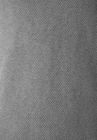 Tessuto grigio intrecciato che presenta un motivo testurizzato. Il materiale mostra una fine struttura a griglia, creando un aspetto superficiale leggermente ruvido.
