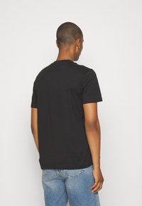 Black short-sleeve t-shirt made of cotton, featuring a classic crew neck and a relaxed fit, paired with light blue jeans.