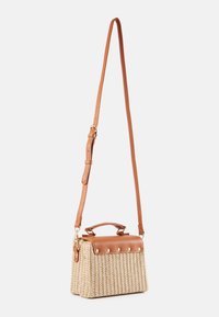 Petit sac bandoulière beige tissé avec rabat en cuir marron, poignée supérieure et sangle d'épaule réglable sur fond blanc.