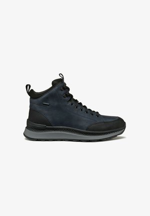 Botas de media caña hechas de cuero azul oscuro con acentos de goma negra, con cordones negros y una suela texturizada gris.