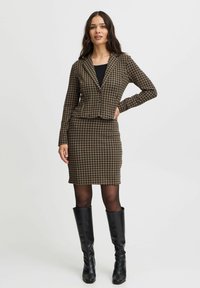 Brauner Hahnentritt-Blazer mit passendem, tailliertem Rock, kombiniert mit schwarzen knielangen Stiefeln; verfügt über einen angeschnittenen Kragen und lange Ärmel.