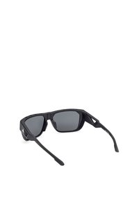 Ochelari de soare sport neagră cu rame unghiulare și lentile de culoare gri închis. Accente laterale texturate și un design flexibil îmbunătățesc durabilitatea.