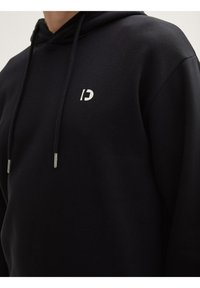 Felpa con cappuccio nera realizzata in tessuto morbido. Presenta un logo bianco sul petto, cordini con punte in metallo e una vestibilità rilassata.