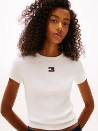 White ribbed short-sleeve t-shirt featuring a small, colorful "Tommy Jeans" logo on the chest. Smooth texture and fitted design.