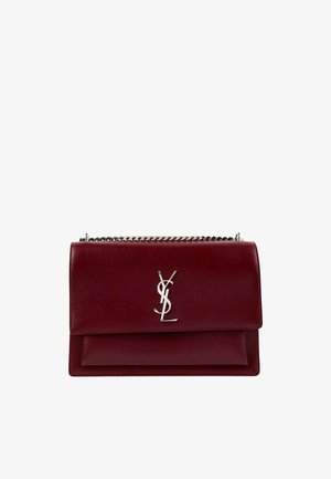 Donkerrode leren designertas met zilveren YSL-logo en zilveren kettingband op een witte achtergrond.