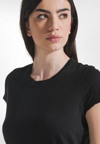 Camiseta negra de manga corta con cuello redondo clásico, hecha de una tela suave, ligeramente ajustada alrededor de los hombros y el busto.