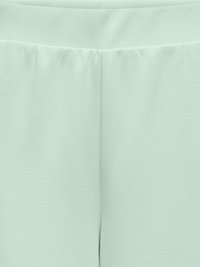 Heledad roheline retuus läikivast ja painduvast kangast. Omab elastset vöökoharihma ja lihtsat, sujuvat disaini ilma nähtavate õmblusteta.