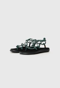 Sandale cu bretele subțiri, de culoare verde închis, cu curele tip cordon peste o talpă neagră, căptușită. Au un design minimalist și un suport pentru picior texturat.