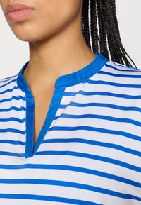 Bluo-bijeli prugasti materijal s gornjim dijelom u obliku slova V, koji ima čvrsti plavi ovratnik i glatku teksturu.