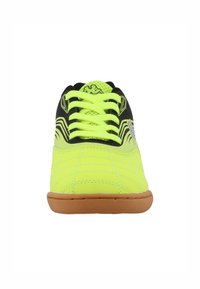 Scarpa sportiva verde lime con colletto a rete nera, lacci piatti e suola in gomma; presenta design a linee diagonali sui lati.