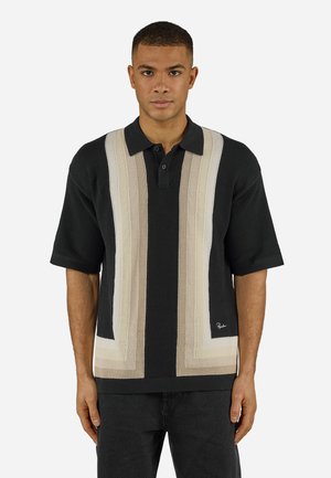 Man draagt een zwart gebreide polo met korte mouwen en beige en crèmekleurige verticale strepen, staand tegen een effen witte achtergrond, gezicht naar voren.