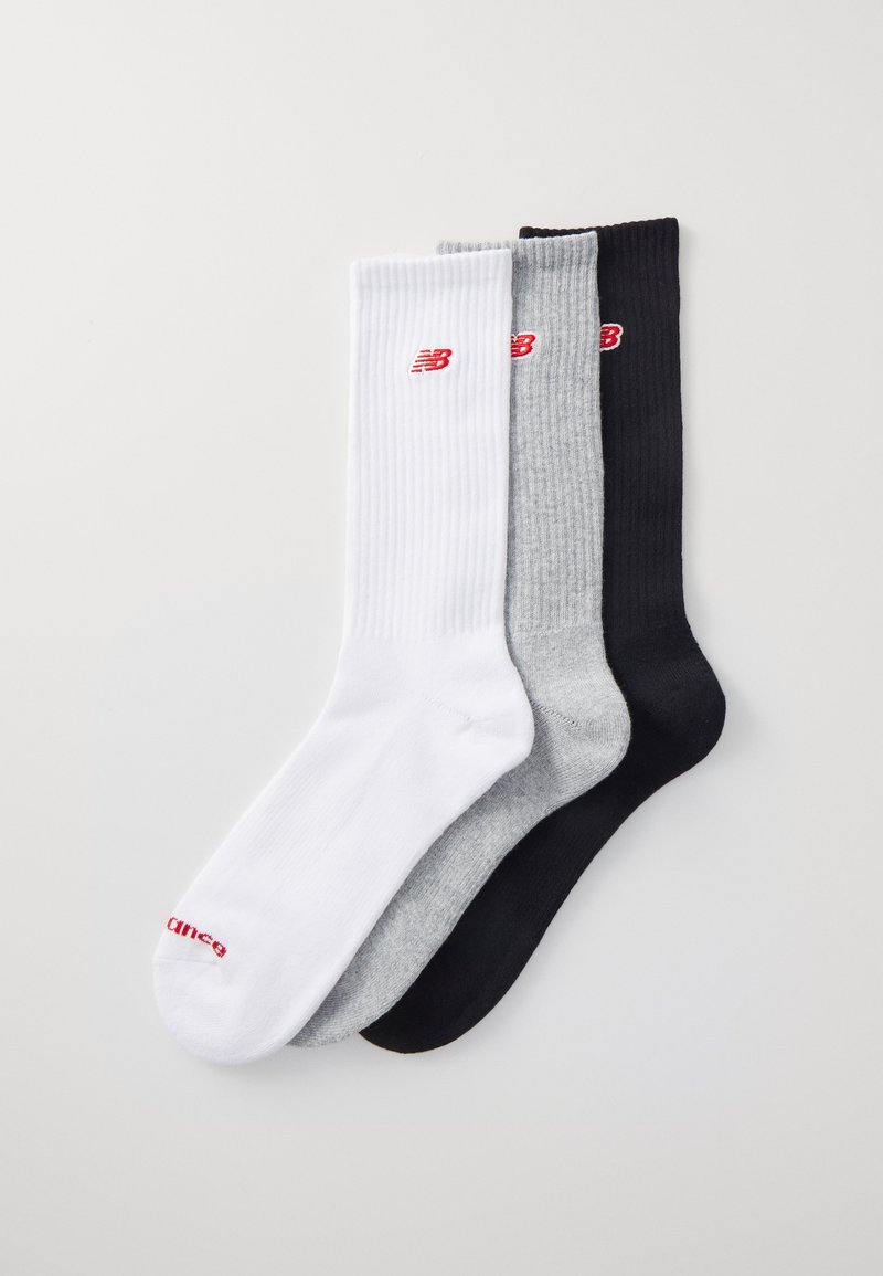 Tre par af ankelstrømper i hvid, grå og sort, med ribbet tekstur og små røde "New Balance" logoer på hver par.