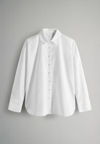 Camicia bianca a maniche lunghe realizzata in tessuto leggero, con colletto a punta, chiusura frontale con bottoni e orlo arrotondato con spacco laterale.