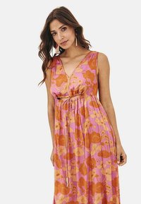 Vestido maxi floral de tela rosa con grandes flores naranjas, escote en V profundo, diseño sin mangas y un lazo en la cintura para ajuste.