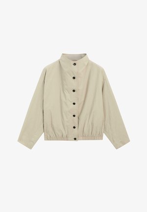 Hellbeige Jacke mit Knopfleiste, hohem Kragen, langen Ärmeln und elastischem Saum, flach auf einem weißen Hintergrund ausgebreitet.