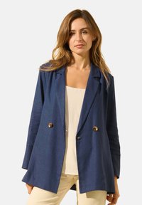 Blazer en lin bleu marine avec un design à double boutonnage, des poches à rabat et des boutons marron. Coupe ajustée, texture lisse et revers cranté.