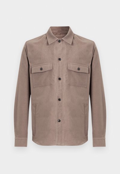 Brun skjorte med knapper laget av mykt stoff. Har to frontlommer, krage og knappelukking foran.