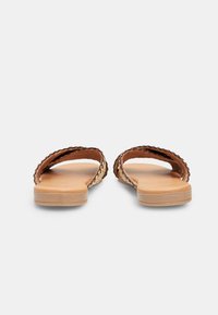 Tan sandals with two curved straps, woven-like texture and smooth soles, featuring a flat design and understated stitching details.