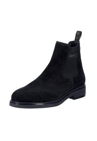 Černá semišová chelsea obuv s elastickými bočními panely, zaoblenou špičkou a poutkem pro snadné obouvání. Plochá podrážka a minimální detaily šití.
