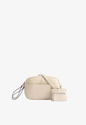 Kremowa skórzana torebka crossbody z odczepianym etui na karty, kieszenią zapinaną na zamek oraz gładką teksturą. Posiada długi regulowany pasek.