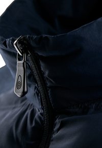 Cuello de chaqueta acolchada azul marino con una cremallera negra y lisa con una lengüeta circular, y tejido suave y texturizado con detalles fruncidos.