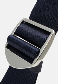 Granatowy pleciony pasek z tkaniny z metalową klamrą w kolorze srebrnym, charakteryzującą się gładkim wykończeniem i dwiema teksturowanymi sekcjami w formie wałków.