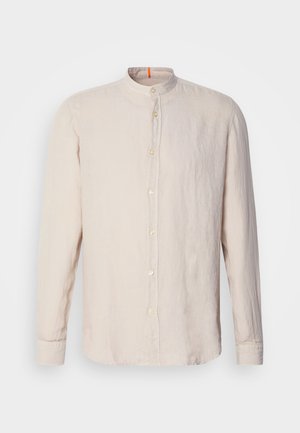 Világos bézs színű vászon, hosszú ujjú ing, band gallérral, elülső gombos záródással és diszkrét textúrával. Narancssárga akcentus a nyakkivágásnál.