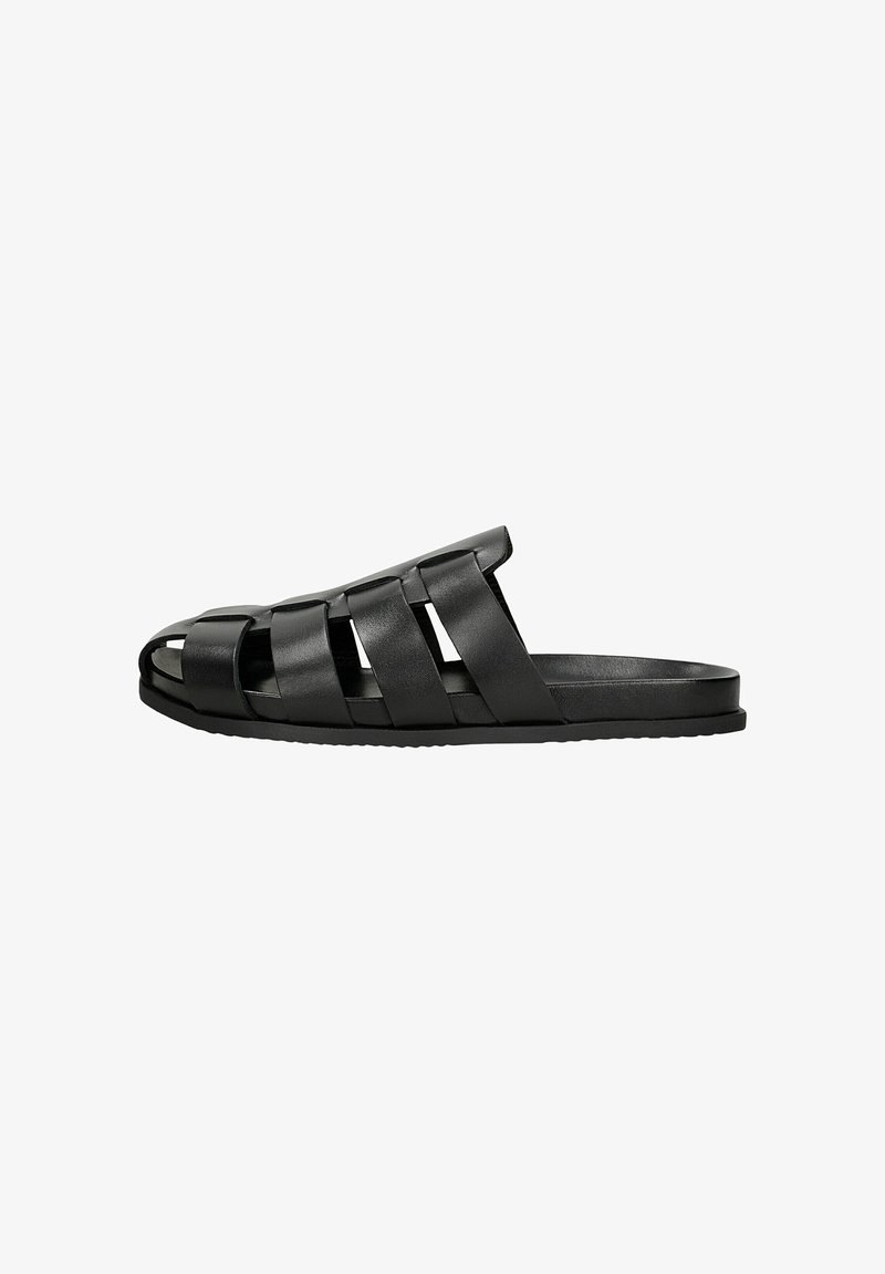 Sandale noire slip-on avec quatre larges brides horizontales et semelle plate, design minimaliste adapté à une tenue décontractée.