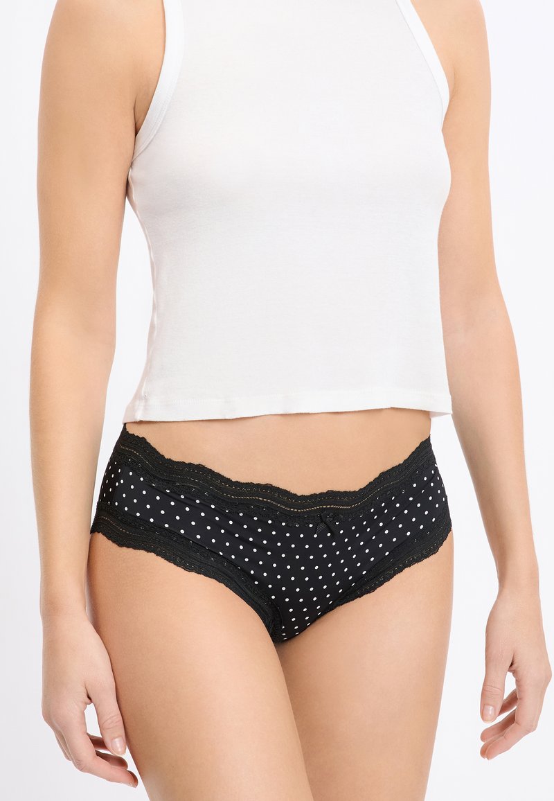 Schwarze Unterhose mit weißen Tupfen und feiner Spitzenverzierung am Bund, mit glatter Textur und klassischer Slipform.