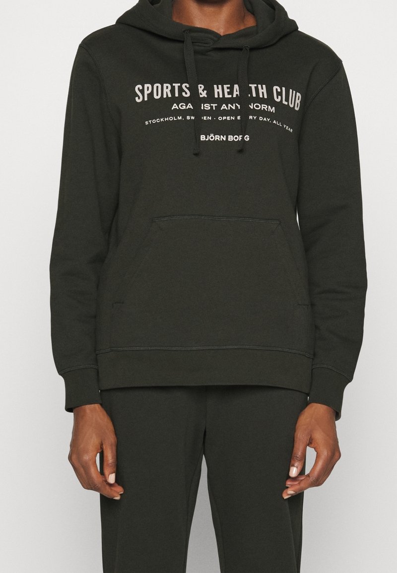 Sweat à capuche vert foncé en coton avec une poche avant, arborant un texte blanc : "SPORTS & HEALTH CLUB" et une poche kangourou.