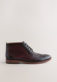 Dunkelbrauner Leder-Stiefel bis zum Knöchel mit Flügelflug-Design, Brogue-Details, Schnürsenkeln und einer kontrastierenden, helleren braunen Außensohle.
