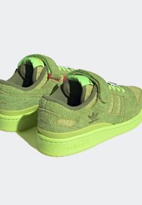 Pár světle zelených tenisek Adidas z texturované semišové látky, s tlustými podrážkami a suchými zipy na jednoduchém světlejším pozadí.