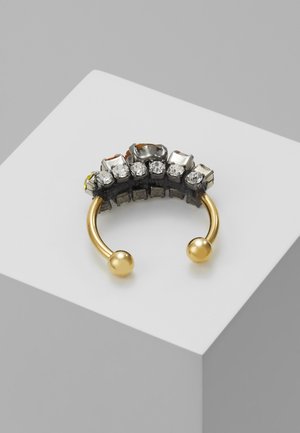 Boucle d'oreille ouverte en or avec une rangée de pierres précieuses transparentes taillées en carré, serties dans une base noire, reposant sur une surface blanche.