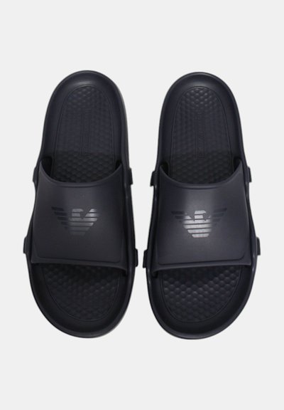 Černé gumové sandály s texturovanou stélkou, širokými popruhy a logem se horizontálními pruhy různé tloušťky.