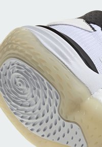 Suela de zapatilla con una suela exterior de goma translúcida, patrón circular texturizado y una entresuela blanca acolchada con acentos negros.