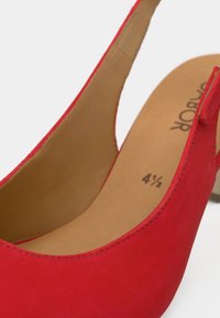 Κόκκινο τακούνι με φελτ από σουέντ με σφήνα, στρογγυλερή ανοιχτή μύτη, ανοιχτό καφέ εσωτερική σόλα και σφραγισμένο μέγεθος "4½". Ομαλή υφή με μινιμαλιστικό σχεδιασμό.