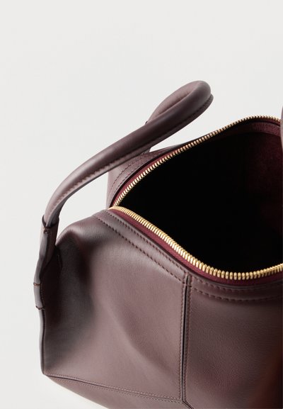 Bolso de cuero marrón oscuro con asas redondeadas y cremallera dorada abierta que muestra un interior vacío sobre un fondo blanco.