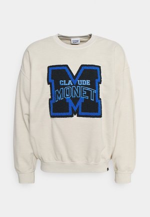 Cream-colored sweatshirt featuring a large blue and black textured “M” with the text “CLAUDE MONET” below it. Ribbed cuffs and hem.