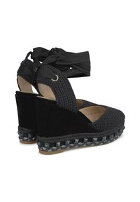 Espadrillas nere a zeppa con design in tessuto intrecciato e suede, dotate di cinturini incrociati e dettaglio intrecciato sulla suola.