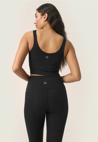 Top corto nero e leggings realizzati in un materiale elastico, caratterizzati da un design senza cuciture e un piccolo logo sul retro di ciascun pezzo.