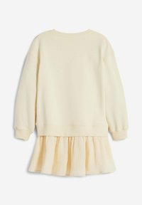 Felpa color crema con una gonna a strati svasata e strutturata. Tessuto morbido e leggero, scollo rotondo e maniche lunghe.